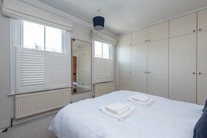 Ein Schlafzimmer mit einem Bett, einem großen Kleiderschrank und einem Spiegel.