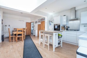 Eine moderne Küche mit weißen Schränken, einem eingebauten Backofen und einem Edelstahlkühlschrank.