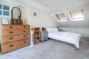 A bedroom with a bed, dresser, nightstand, and a radiator. There are skylights and a ceiling fan. - Charming 2BDR Terraced House with Garden Wimbledon (Greater London)