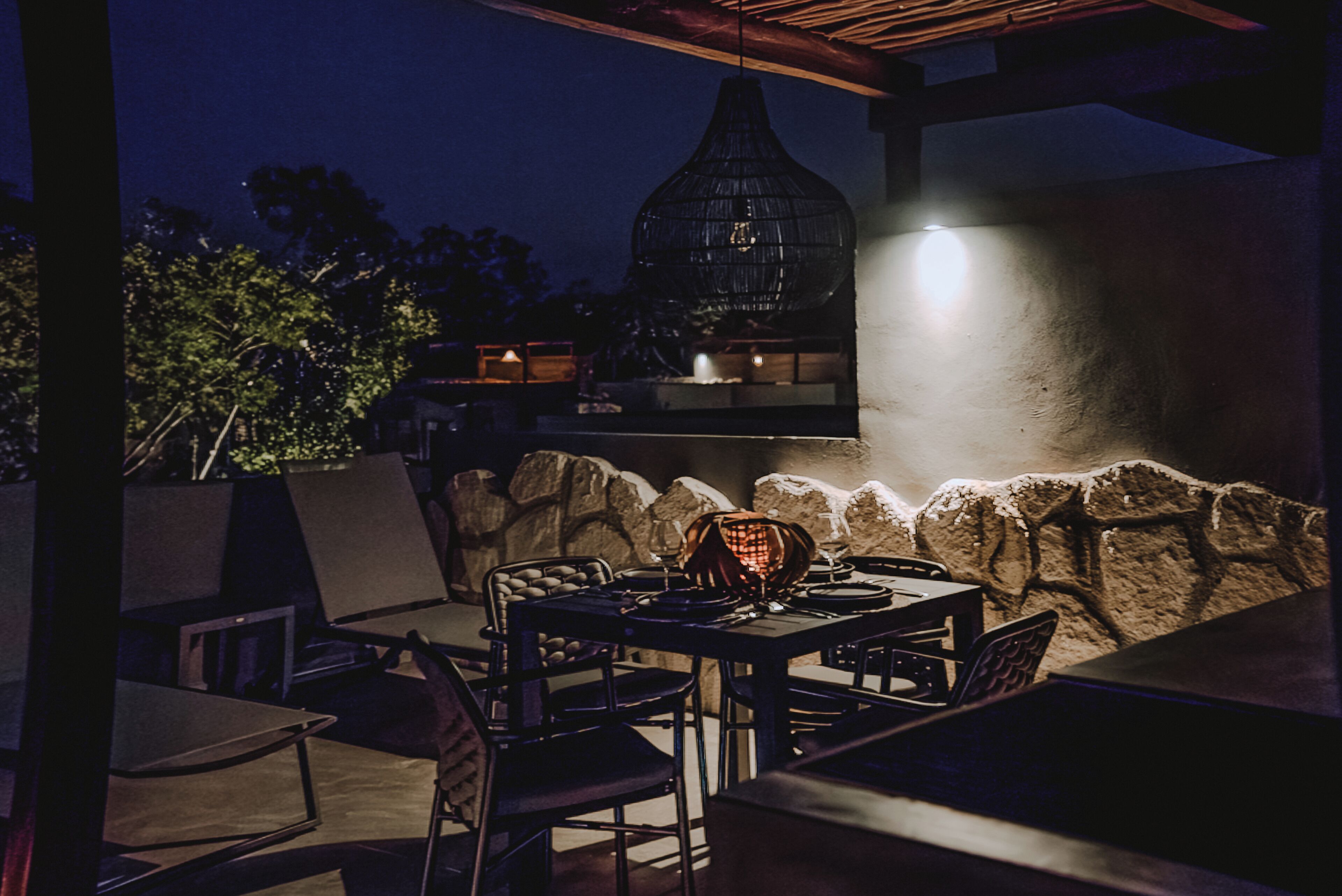 An outdoor patio with stone walls, a hanging light fixture, and a grill.