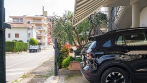 Een zwarte SUV geparkeerd in een woonwijk met een straat, huizen en een trap die naar een balkon leidt.