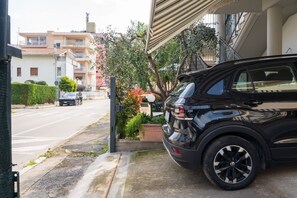 Ein schwarzer SUV geparkt in einer Wohngegend mit Straße, Häusern und einer Treppe, die zu einem Balkon führt.