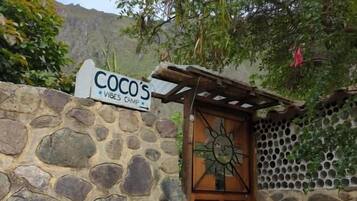 Un muro de piedra con una puerta de madera y un cartel que dice 'COCO'S VIBES CAMP'.