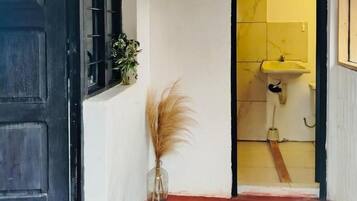 A hallway with a black door, a yellow tiled wall, and a sink visible through an open door.