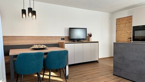 Une cuisine moderne avec un plan de travail en bois, un four encastré et un téléviseur posé sur un meuble.