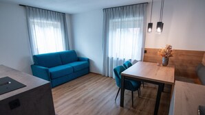 Une chambre moderne avec un canapé bleu, une table à manger avec des chaises et une tête de lit en bois.