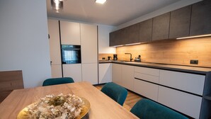 Une cuisine moderne avec un plan de travail en bois, un évier et une machine à café. On y trouve une table à manger avec des chaises et un élément décoratif au centre.