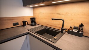 Une cuisine moderne équipée d’un évier intégré, d’une machine à café et d’un bloc à couteaux.