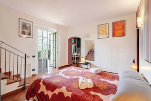 Habitación de hotel con cama, escritorio, silla, escalera y puerta que da a un balcón.