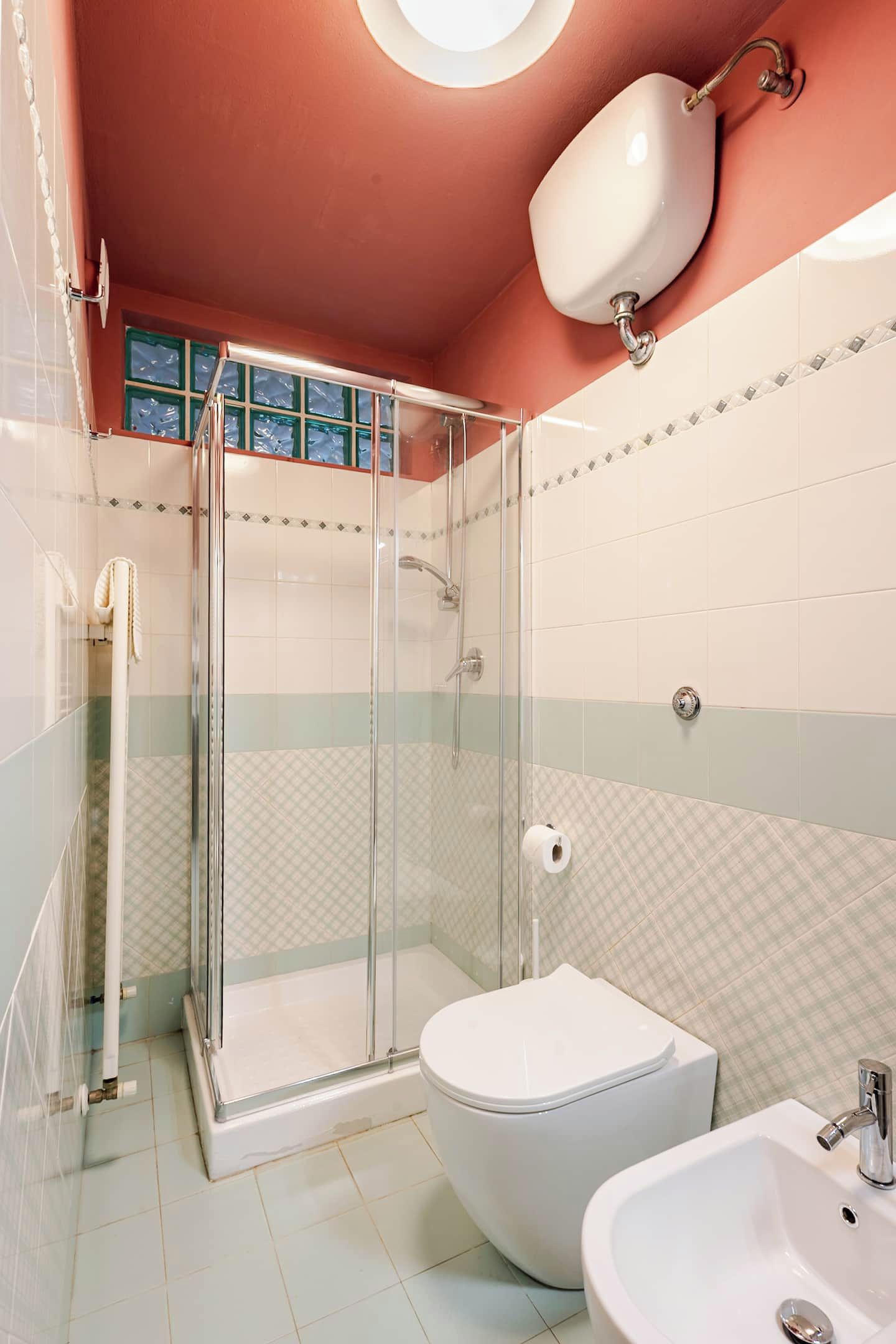A bathroom with a glass-enclosed shower, a toilet, and a sink.