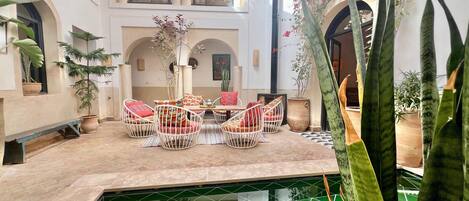 Un patio con piscina, paredes blancas, arcos y plantas en macetas.