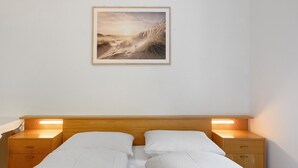 Ein Bett mit zwei Nachttischen, einem gerahmten Bild an der Wand und einem Holzkopfende.