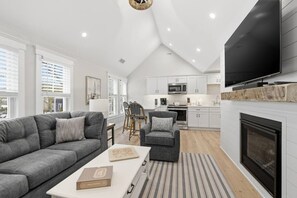 A modern living room with a grey sofa, a coffee table, and a fireplace. - LUX on Main | Downtown | Parking | Sleeps 6, #203 (Falmouth)