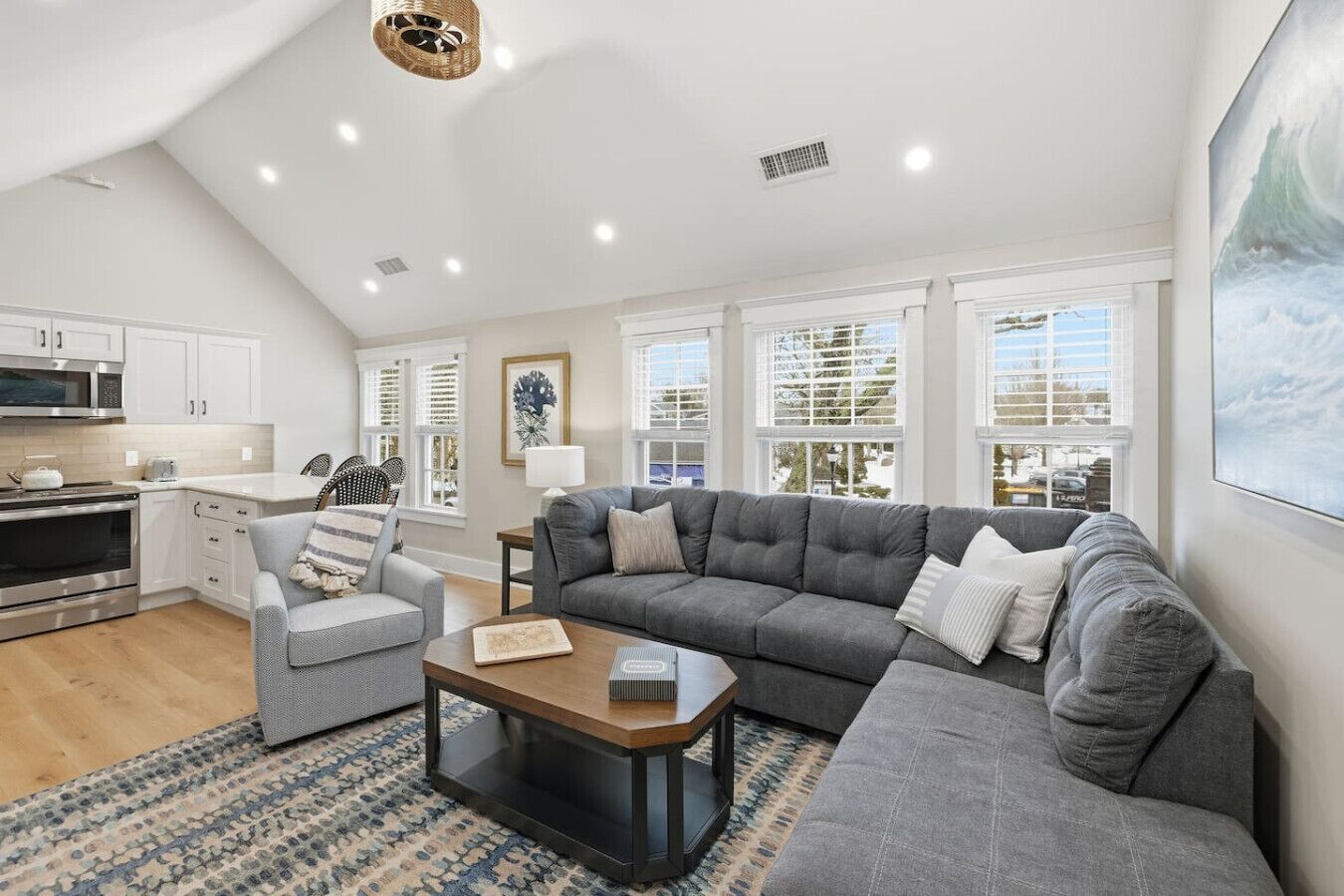 A spacious living area with a gray sofa, a coffee table, and a kitchen in the background.