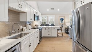 Een moderne keuken met witte kasten, roestvrijstalen apparatuur en een houten vloer.