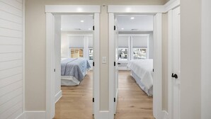 Un corridoio che conduce a due camere da letto con pavimento in legno e pareti bianche.