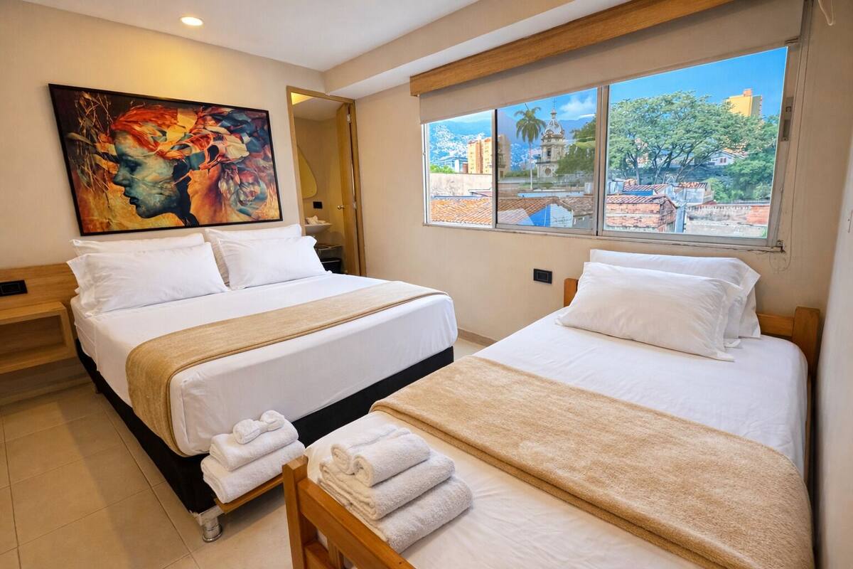 Habitació d'hotel amb dos llits, una finestra gran que dona a una vista de la ciutat i un quadre a la paret.