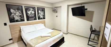 Una habitación de hotel moderna con una cama, un televisor y arte abstracto en la pared.