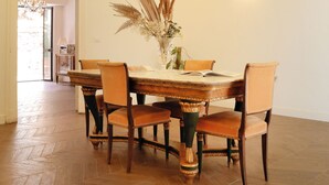 A dining room with a wooden herringbone floor, a central table with chairs, and a decorative ceiling. - BERETTI HOME (Catania)