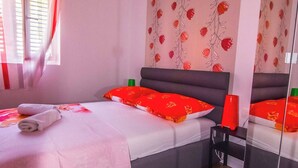 A bedroom with a bed, a bedside table, a mirror, and a window with curtains. - Marli Beach Apartments Jesenice Marli 1 (Dugi Rat)