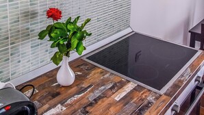 A kitchen with a modern stove, a white vase with a red flower, and a stainless steel range hood. - Marli Beach Apartments Jesenice Marli 1 (Dugi Rat)