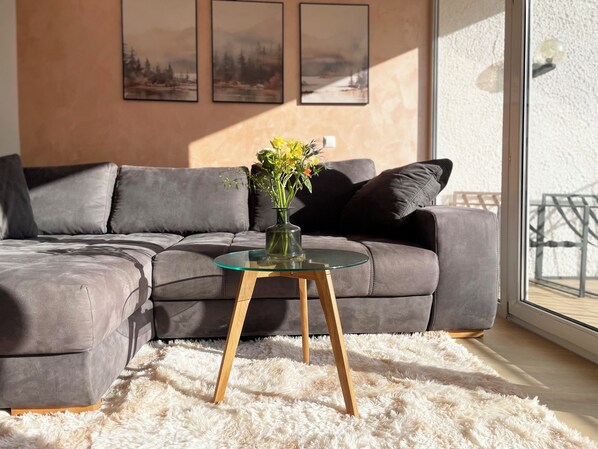 A modern living room with a grey sectional sofa, a glass coffee table, and a fluffy white rug. - Beautiful apartment Traumblick with balcony Bad Ems (Bad Ems)