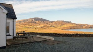 A building with a stone wall and a gravel patio. - Solas Alainn -  a detached house that sleeps 6 guests  in 3 bedrooms (Staffin)