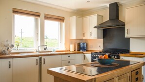 A modern kitchen with a central island, a stove, and a large window providing natural light. - Solas Alainn -  a detached house that sleeps 6 guests  in 3 bedrooms (Staffin)