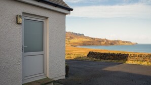 A coastal building with a white exterior, a door, and a stone wall.