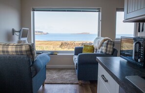 Une pièce confortable avec vue sur la mer, comprenant un canapé, un fauteuil, une petite table et un four à micro-ondes.