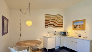 Uma cozinha moderna com área de refeições, armários brancos, uma mesa redonda e um lustre.