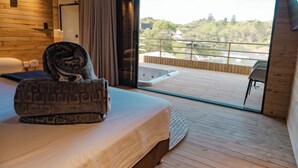 A bedroom with a bed, a towel, a window, and a balcony with a view of a landscape. - Okai by Bernalo Hotels (Guatape)