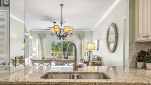 A kitchen with granite countertops, a stainless steel sink, a chandelier, and a view of the outdoors. - 2BR condo with pool view & beach access (Miramar Beach)