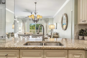 A kitchen with granite countertops, a stainless steel sink, a chandelier, and a view of the outdoors. - 2BR condo with pool view & beach access (Miramar Beach)