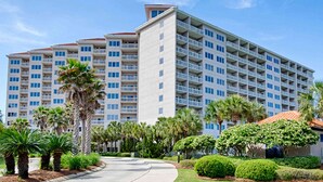A multi-story hotel with balconies, palm trees, and a well-maintained garden. - 2BR condo with pool view & beach access (Miramar Beach)