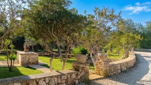 Un jardín ajardinado con muros de piedra, un columpio y diversos árboles.