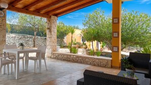 Un patio al aire libre con paredes de piedra, un espacio de estar cubierto y plantas en macetas.