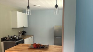 A modern kitchen with a wooden island, two red chairs, pendant lights, and a stainless steel refrigerator. - Comfortable, quiet apartment! Minutes from the airport, beaches and restaurants (Carolina)