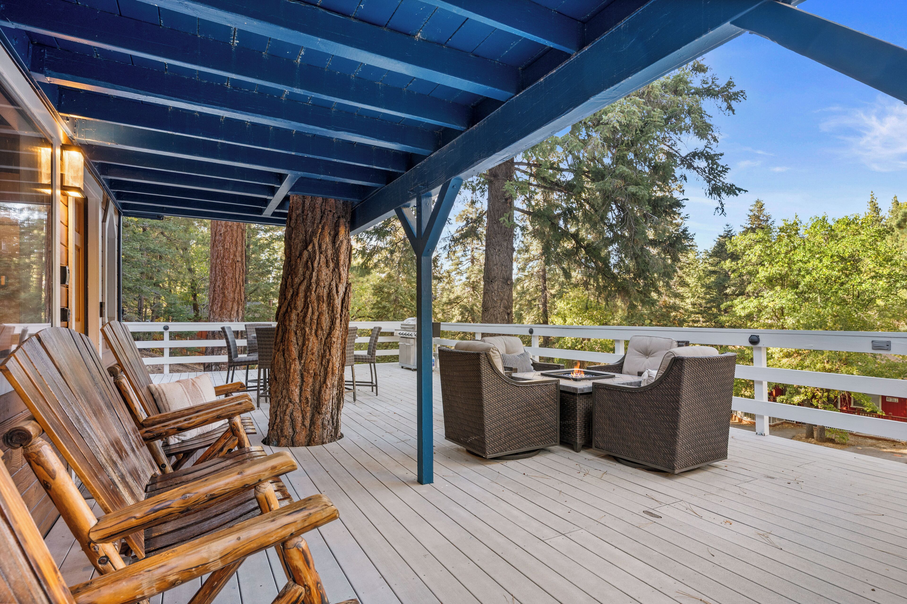 A wooden deck with outdoor furniture, including chairs and a sofa, under a blue roof.