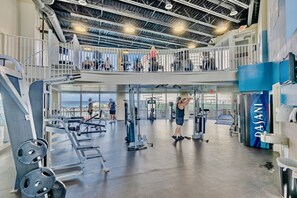 A multi-level gym with various exercise equipment, a view of the ocean, and a blue wall with the word "PASANI". - Resort Condo w/ Pools, Hot Tubs & Beach Access (Panama City Beach)