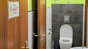 Un baño con inodoro, lavabo y un cartel en la puerta.