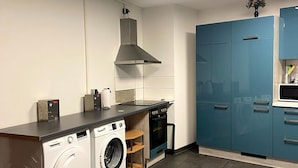 Una cocina moderna con lavadora y secadora integradas, estufa y armarios azules.