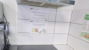 Una cocina comercial con campana extractora de acero inoxidable, horno empotrado y salpicadero de azulejos.