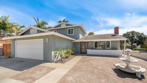 Ein zweigeschossiges Haus mit Garage, einem kleinen Anbau und einem gepflasterten Auffahrt.