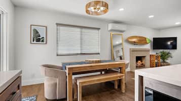 Un salon moderne avec une table à manger en bois, un canapé, une cheminée et un téléviseur fixé au mur.