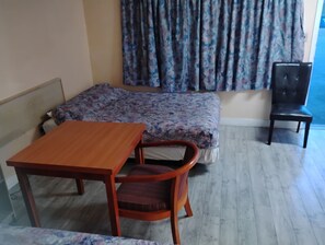 A room with a bed, a wooden table, a chair, and a black chair.