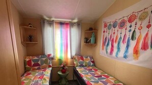 Una stanza piccola e accogliente con due letti, un tappeto, un arazzo e una finestra con tende.