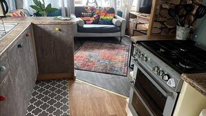 Una cucina compatta con fornello, forno e pensili in legno.