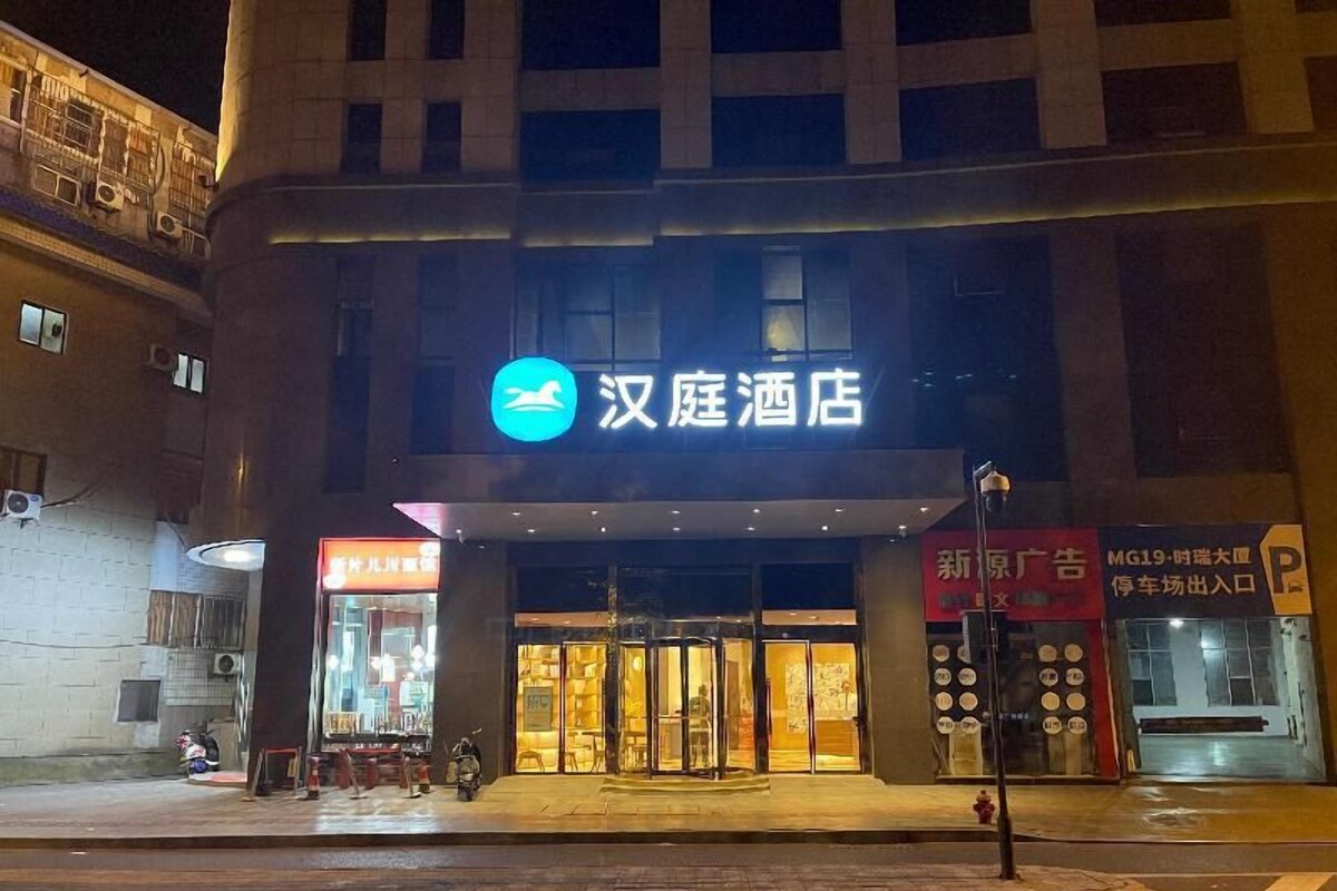 Ein Hotel Eingang mit einem Schild, auf dem '汉庭酒店' steht, und einer sichtbaren Eingangstür.