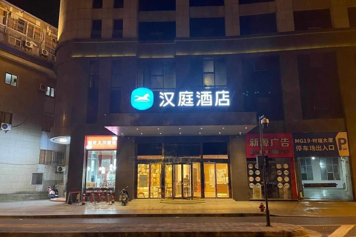 A hotel entrance with a sign reading '汉庭酒店' and a parking sign nearby.